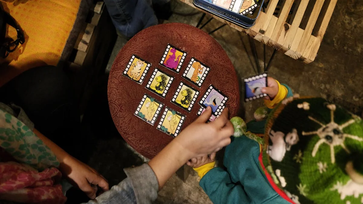 A child shows a parent a physical trading card they designed and printed themselves